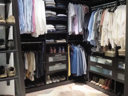 Neatly organized walk-in closet with folded clothes and paired shoes